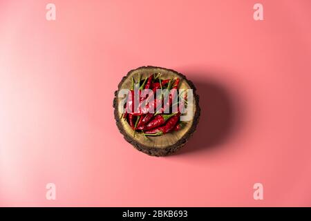 Hot pepper in wooden bowl on pink background. Top view of dry and raw chillies. Healthy, organic and aromatic food ingredient of Mexican, Indian. Stock Photo