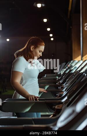 concentrated overweight girl training on treadmill in gym Stock Photo