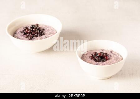 Two oatmeal bowls with blueberries for healthy breakfast isolated. Stock Photo
