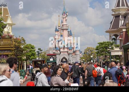 Standing on a street of a theme park in middle of a crowd of people. Staying in park in front of a cute castle with visitors. Paris France, 29. May 20 Stock Photo