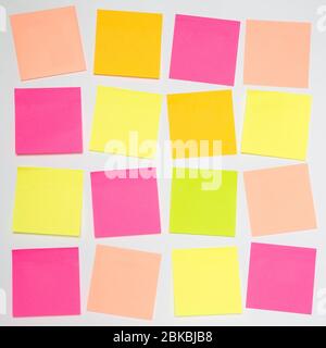 A square grid pattern with lots of blank, colourful sticky notes or adhesive note paper on a white background with copy space Stock Photo