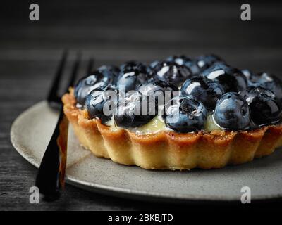 close up of blueberry tart on dark wooden table Stock Photo