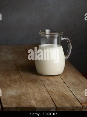 milk jug on old wooden kitchen table Stock Photo