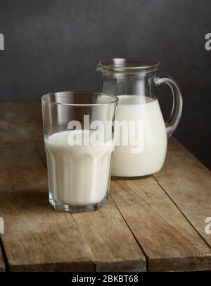 milk jug and glass on old wooden kitchen table Stock Photo