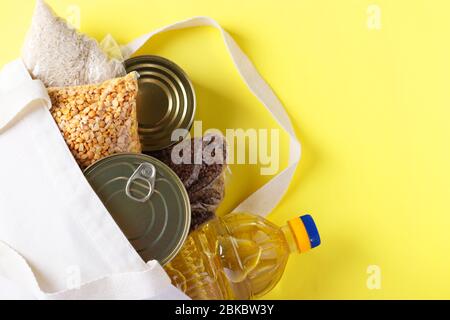 Food delivery, Donation. Textile Bag with food supplies crisis food stock for quarantine isolation period on yellow background. Rice, buckwheat, peas Stock Photo