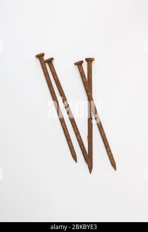 Group of four long rusty nails against plain white background Stock Photo