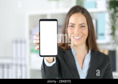 Happy executive woman showing blank smart phone screen standing at office Stock Photo