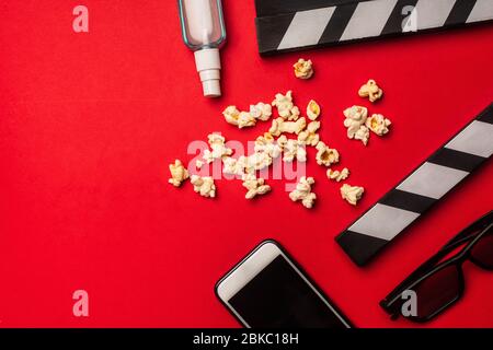 Top view of smartphone near clapperboard, popcorn and hand sanitizer on red background Stock Photo