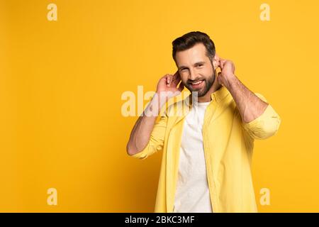 Smiling man showing gesture in deaf and dumb language on yellow background Stock Photo