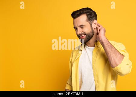 Smiling man with closed eyes showing gesture from deaf and dumb language on yellow background Stock Photo