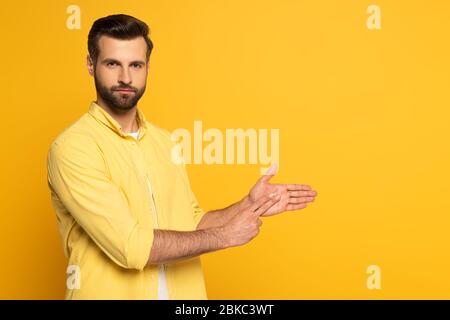 Handsome man gesturing while using sign language on yellow background Stock Photo