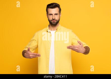 Man looking at camera while using deaf and dumb language on yellow background Stock Photo