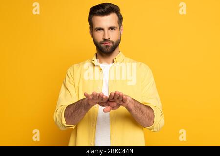 Young man using deaf and dumb language on yellow background Stock Photo