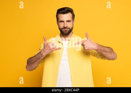 Man looking at camera while using deaf and dumb language on yellow background Stock Photo