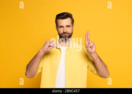 Bearded man showing letters while using deaf and dumb language on yellow background Stock Photo