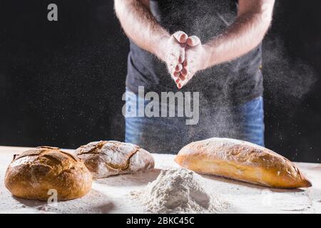 Baker cooking bread. Man slaps flour. Food concept. Stock Photo