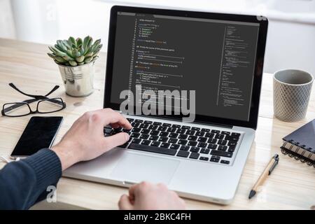 Computer code, software concept. Programmer working with a laptop, programming code on the screen, office background. Developing coding technologies. Stock Photo