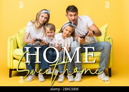 KYIV, UKRAINE - MARCH 4, 2020: cheerful family playing video game with joysticks while sitting on sofa on yellow, home sweet home illustration Stock Photo