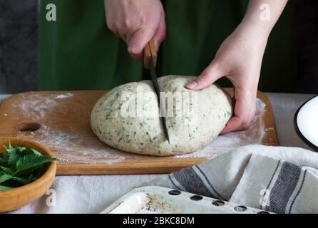 A woman is preparing buns from yeast dough with nettles. Rustic style. Stock Photo