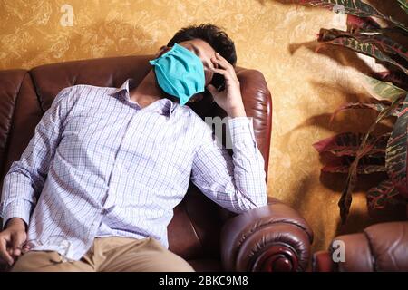 A sick man with a mask on his face resting on sofa  Stock Photo