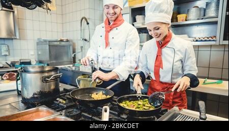 Team of chefs in a kitchen preparing fantastic food in pans Stock Photo