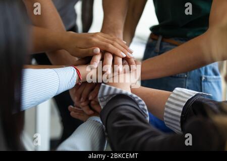 Close up multiracial business people putting hands together, showing support. Stock Photo