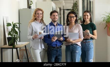 Portrait of standing smiling team with documents looking at camera. Stock Photo