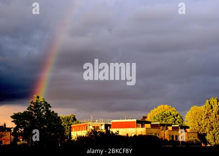 Rainbow over London flats Arch in the sky made from different colours that forms when sun rays are refracted by rain drops The pattern starts with red Stock Photo