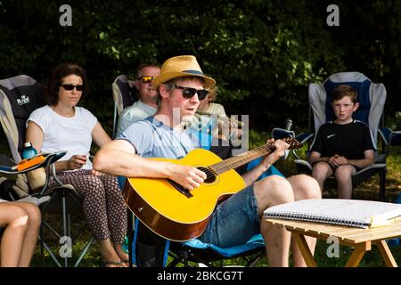 Family singing songs with acoustic guitar on a summer camping holiday at Wowo's, a family campsite in Sussex Stock Photo