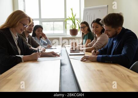 Smiling adult businesswoman signing up documents with serious businessman.