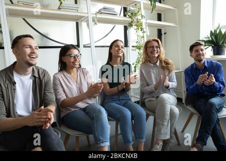 Diverse happy team applauding sitting at conference clapping hands. Stock Photo