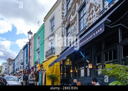 Portobello Road, crowded with people  shopping  & dining at Gold restaurant & bar with mural of Eye Contact on façade of building, Notting Hill,London Stock Photo
