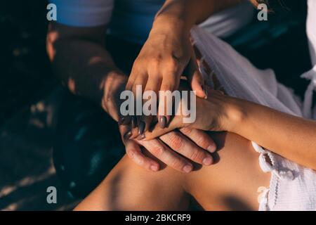 A man's hand on the knee of a woman who put her hands on his arm. Woman in white dress and man in blue jeans and white T-shirt. Couple on valentines d Stock Photo