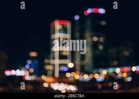 Abstract bokeh of buildings at night. Blurred photo of cityscape. Defocused background. Office building in city center. Different colors of bokeh Stock Photo