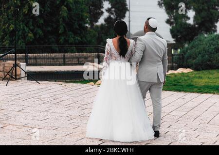 The bride and groom in a bale on back in Israel. Jewish wedding. Newlyweds are photographed during a wedding. Man and woman holding hands, rear view. Stock Photo