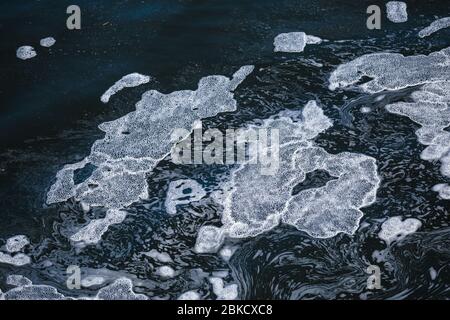 Foam islands on the water close-up view. Dark blue spring water with white foam structures Stock Photo