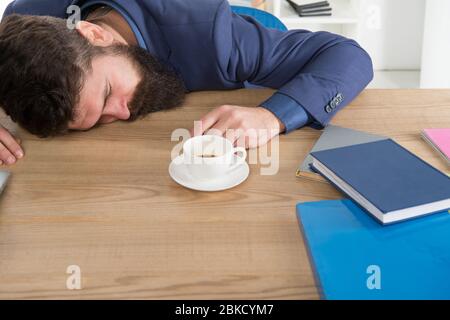 Tired businessman sleep in office. boss fell asleep on table. Man sleeping over workplace. coffee will help me. bored and exhausted guy sleep at work. need break for relax. being lazy. Stock Photo