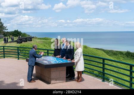 President Donald J. Trump and First Lady Melania Trump, joined by French President Emmanuel Macron and his wife Mrs. Brigitte Macron, receive a briefing on Omaha Beach at the map table by the Superintendent of the Normandy American Cemetery, Scott Desjardins Thursday, June 6, 2019, at the Normandy American Cemetery in Normandy, France. President Trump at DDay75 Stock Photo