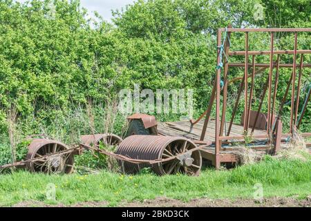 Idle ridged roller farm machinery in corner of sunlit field. For UK farming & agriculture, farm closures, collapse of agriculture, abandoned farmland. Stock Photo