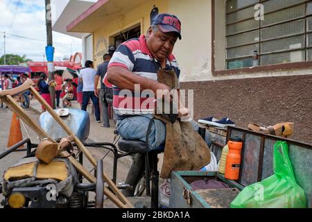 Traditional shoemaker repairing old shoes in the streets of the Tizmin market. Stock Photo