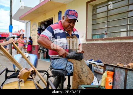 Traditional shoemaker repairing old shoes in the streets of the Tizmin market. Stock Photo