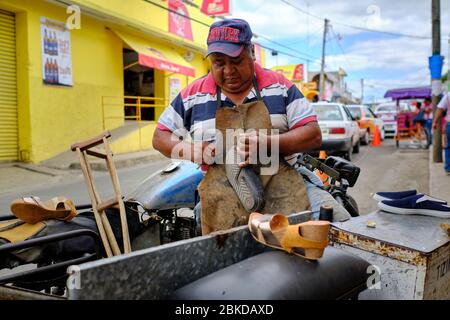 Traditional shoemaker repairing old shoes in the streets of the Tizmin market. Stock Photo