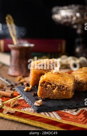 Baklava sweets on a black stone with coffee and books, binoculars at the back