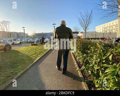 Strasbourg, France - Jan 20, 2020: Rear view of senior man walking with canes in large French hospital parking Stock Photo