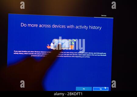London, United Kingdom - Mar 28, 2020: Man selecting Do more across devices hand POV touching the touchscreen of a modern Microsoft Windows PC computer during the update of the OS operating system Stock Photo
