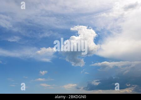 White fluffy cumulus, stratus and cirrus clouds floating slowly high in the blue sky on a sunny day. Meteorology, weather and different cloud type Stock Photo