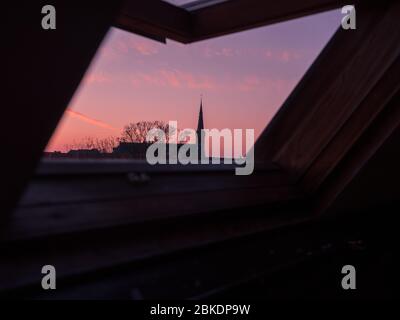 Close up view through open roof window. Cathedral and tree on sunset sky background. The Hague, Netherlands Stock Photo