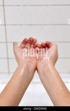 The child enjoys falling drops water, collecting them in the palm of his hand, stretched out in the center. Stock Photo