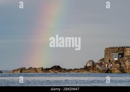 Rainbow over the rocks and swimmers changing at the famous Forty Foot bathing place at Sandycove near Dublin in Ireland Stock Photo