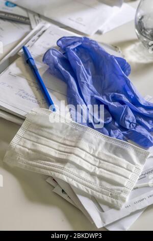 Corona virus mask with blue gloves on a kitchen counter with a pen and mail Stock Photo